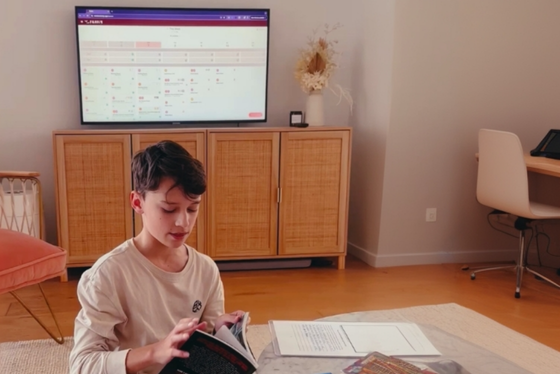 Boy homeschooling with Freely Learning Centre in Freely homeschool tracking app being displayed on the tv